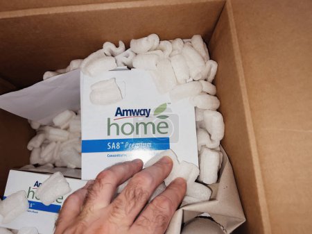 Foto de Paris, France - Sep 12, 2022: Male hand inside the parcel with Amway detergents goods - online e-commerce orders with SA8 Premium - Imagen libre de derechos