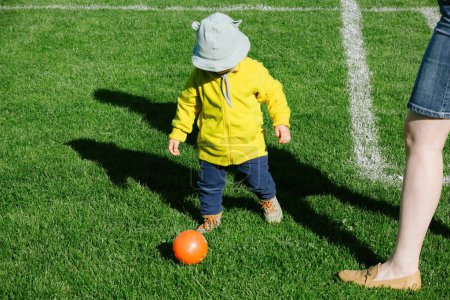 Foto de Overhead view of toddler playing soccer football with his mother - cute bear sun protection hat - Imagen libre de derechos