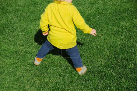 Photo for Abstract rear view of funny toddler playing soccer football in green lawn backyard - Royalty Free Image