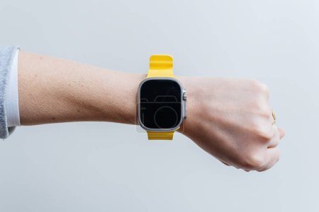 Foto de London, United Kingdom - Sep 28, 2022: POV woman hand wearing new luxury Apple Watch Series Ultra on her wrist black screen white background - Imagen libre de derechos