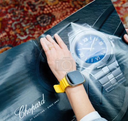 Photo for London, United Kingdom - Sept 28, 2022: View from above of fashionable woman looking at large watch advertising inside How To Spend It HTSI by Financial Times wearing new Apple Watch Ultra by Apple - Royalty Free Image
