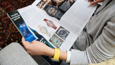 Foto de London, United Kingdom - Sept 28, 2022: Overhead of Fashionable woman looking at large watch advertising inside How To Spend It HTSI by Financial Times wearing new Apple Watch Ultra by Apple Computers - Imagen libre de derechos