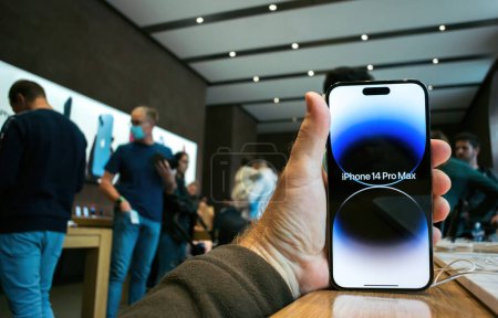 Foto de Paris, France - Sep 22, 2022: Apple launch new smartphone iPhone 14 Pro and iPhone 14 Pro Max - customer holding device in hand in store with large crowd in background - Imagen libre de derechos