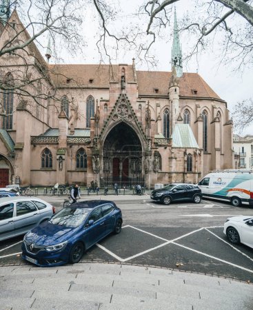 Foto de Strasbourg, France - Jan 5 2023: Renault blue car and white van cars parked in front of Eglise Saint-Pierre-le-Jeune Protestant church in central Strasbourg - Imagen libre de derechos