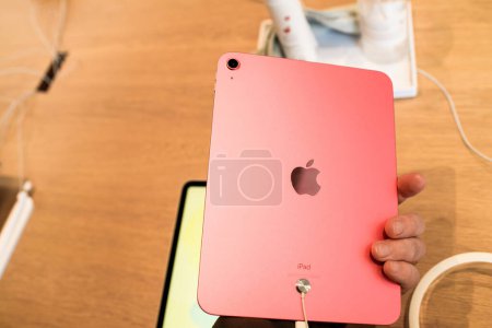 Foto de Paris, France - Oct 28, 2022: Customer male hand close-up of new Apple Computers iPad 10th generation in Pink color in store - looking at the rear camera with big logotype insignia on the back - Imagen libre de derechos