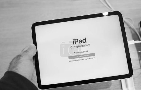 Foto de Paris, France - Oct 28, 2022: Black and white photo of customer male hand close-up of new Apple Computers iPad 10th generation in Yellow color in store - starting price on screen 589 euros - Imagen libre de derechos