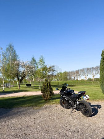Téléchargez les photos : Germany - Aug 18, 2022: Luxury Yamaha YZF-R125 motorcycle parked in front a golf lawn - en image libre de droit