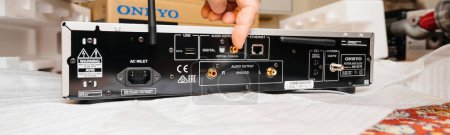 Photo for Paris, France - Dec 13, 2022: POV male hand pointing to digital coaxial gold-plated conneciton on new Onkyo NS-6170 network audio player with DSD Hi-Res Audio and DSD DAB WIFI device after unboxing - Royalty Free Image
