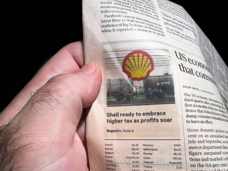 Photo for Paris, France - Oct 29, 2022: Reader hand holding Financial Times column article with Shell ready to embrace higher tax as profits soar - Royalty Free Image