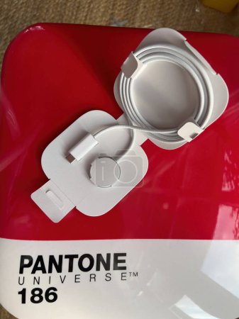 Foto de Paris, France - Oct 18, 2022: View from above of new packaged Apple Watch Magnetic Fast Charger to USB-C cable on red bacakground of a Seletti Pantone Universe 186 chair - Imagen libre de derechos