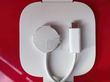 Foto de Paris, France - Oct 18, 2022: Close-up macro shot of new packaged Apple Watch Magnetic Fast Charger to USB-C cable on red bacakground - Imagen libre de derechos