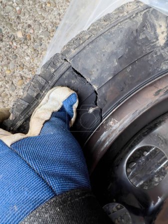 Téléchargez les photos : POV male hand mechanic showing damaged car tyre tire after accident - en image libre de droit