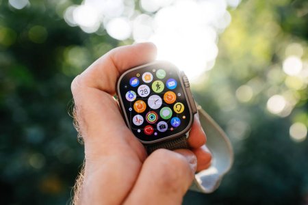 Foto de London, United Kingdom - Sept 28, 2022: Male hand holding new Apple Watch Ultra Smartwatch against defocused bokeh background with all apps on the oled display screen - Imagen libre de derechos