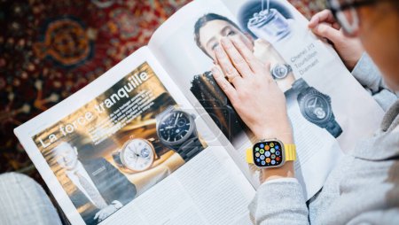 Foto de Londres, Reino Unido - 28 de septiembre de 2022: Mujer de moda que mira la publicidad de relojes grandes en el interior Cómo gastarlo HTSI de Financial Times con el nuevo Apple Watch Ultra de Apple Computers en su - Imagen libre de derechos