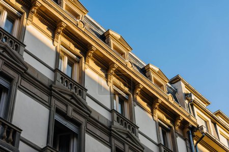 Photo for Low angle side view close-up shot of the upper part of an elegant stone and white Haussmann building with balconies and blue sky in Paris - Royalty Free Image