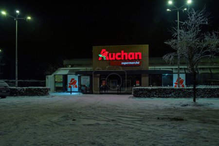 Photo for Strasbourg, France - Dec 19, 2022: Closed Auchan supermarket late at night - covered with snow asphalt parking - Royalty Free Image