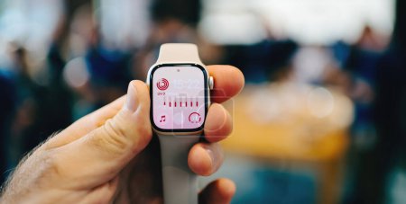 Téléchargez les photos : Paris, France - 28 oct. 2022 : Un homme POV tenant la dernière Apple Watch Series 8 LTE avec des clients déconcentrés en arrière-plan - en image libre de droit
