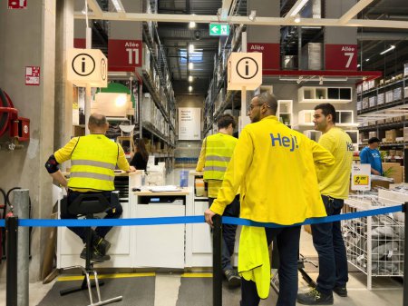Téléchargez les photos : Paris, France - Oct 26, 2022: Ikea male workers inside large warehouse waiting to assist the customers of giant furniture store market - en image libre de droit