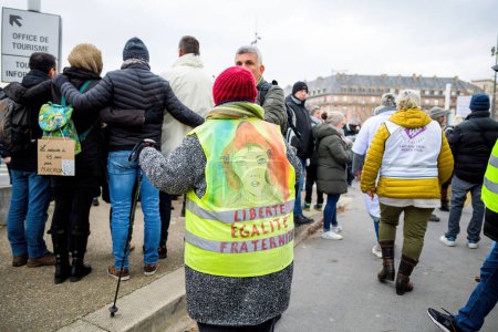 Foto de Strasbourg, France - Jan 19, 2023: Liberte Egalite Fraternite on woman yellow vest at protest against the French governments planned pension reform to push the retirement age from 62 to 64 unions - Imagen libre de derechos