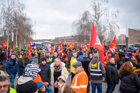 Téléchargez les photos : Strasbourg, France - Jan 19, 2023: Large crowd holding placards, flags at protest against the French governments planned pension reform to push the retirement age from 62 to 64 unions have called for - en image libre de droit