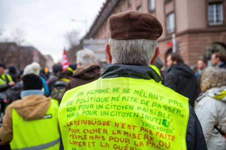 Téléchargez les photos : Strasbourg, France - Jan 19, 2023: Long message by Thucydides on mans yellow vest at protest against the French governments planned pension reform to push the retirement age from 62 to 64 unions - en image libre de droit