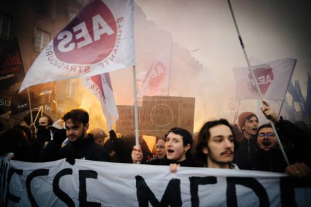 Foto de Strasbourg, France - Jan 19, 2023: Smoke grenade and large crowd at protest against the French governments planned pension reform to push the retirement age from 62 to 64 unions have called for mass - Imagen libre de derechos