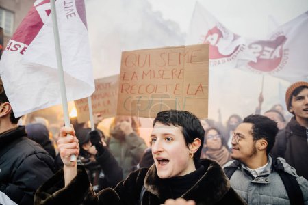 Foto de Strasbourg, France - Jan 19, 2023: Young woman yelling in front of Large crowd at protest against the French governments planned pension reform to push the retirement age from 62 to 64 unions have - Imagen libre de derechos