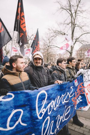 Photo for Strasbourg, France - Jan 19, 2023: Young peoples with placard large crowd at protest against the French governments planned pension reform to push the retirement age from 62 to 64 unions have called - Royalty Free Image