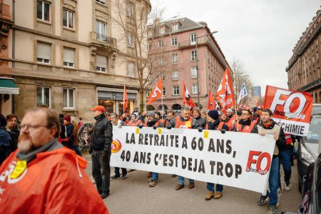 Téléchargez les photos : Strasbourg, France - Jan 19, 2023: Large crowd at protest holding large placard against the French governments planned pension reform to push the retirement age from 62 to 64 - en image libre de droit