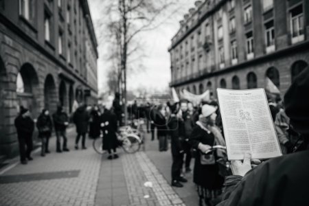 Foto de Strasbourg, France - Jan 19, 2023: Man reading ABC of marxism - migrawtion at protest against the French governments planned pension reform to push the retirement age from 62 to 64 unions have called - Imagen libre de derechos