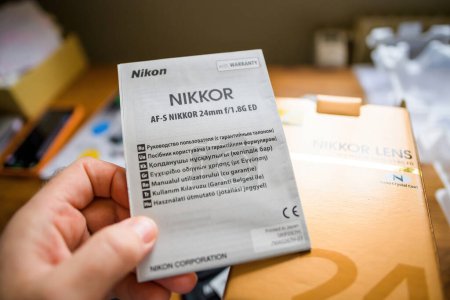Photo for Paris, France - Jan 16, 2023: POV personal perspective male hand holding instruction manual for new NIkon AF-s Nikkor 25mm f 1.8 G ED lens in Russian, Ukrainian, Greek, Romanian Turkish and Hungarian - Royalty Free Image
