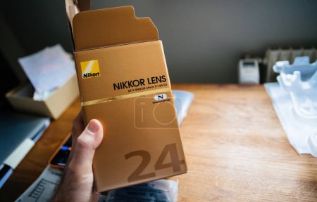 Photo for Paris, France - Jan 16, 2023: POV personal perspective male hand holding cardboard package of open new NIkon AF-s Nikkor 25mm f 1.8 G ED lens for DSLR camera - Royalty Free Image