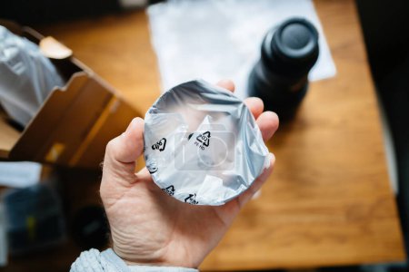 Photo for POV male hand holding new lens hood in the plastic package during unboxing of a new high-performance camera lens in plastic protection - Royalty Free Image
