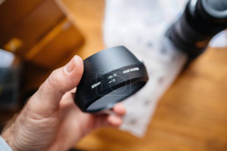 Foto de Paris, France - Jan 16, 2023: View from above of new Nikon HB-76 lens hood in the plastic package during unboxing of a new high-performance camera lens - Imagen libre de derechos