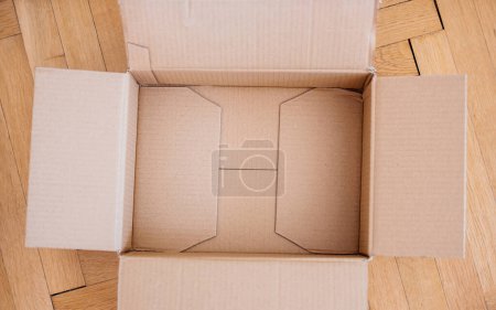 Téléchargez les photos : View from above of empty cardboard package on parquet wooden floor - en image libre de droit