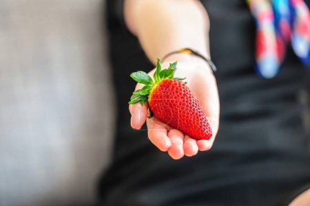 Photo for Close-up macro shot of female hand holding single strawberry - Royalty Free Image