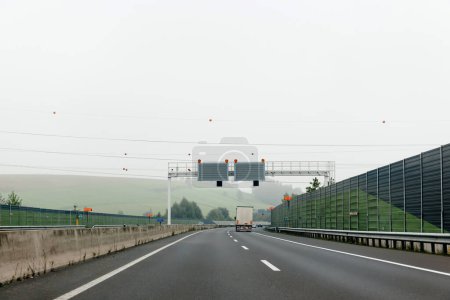 Téléchargez les photos : Highway in the rural Europe with lonely trailer cargo truck driving fast on the multiple lane highway - rear view - en image libre de droit