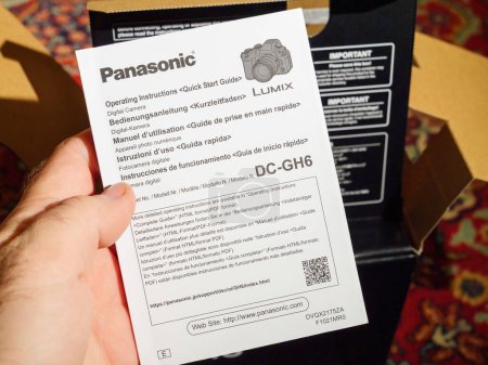 Photo for Paris, France - Dec 2, 2022: Male hand holding operating instruction flyer paper during the unboxing of new Panasonic Lumix GH6 mirrorless camera - Royalty Free Image