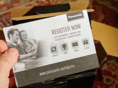 Photo for Paris, France - Dec 2, 2022: Male hand holding Register now flyer paper during the unboxing of new Panasonic Lumix GH6 mirrorless camera - Royalty Free Image