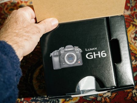 Téléchargez les photos : Paris, France - Dec 2, 2022: New Panasonic Lumix GH6 mirrorless camera package in male hand during first unboxing - en image libre de droit