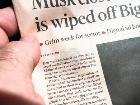 Téléchargez les photos : Paris, France - Oct 29, 2022: Close-up male hand reading Financial Times newspaper with article about Elon Musk taking the elite club of social media barons after clinching a 44bn takeover of Twitter - en image libre de droit