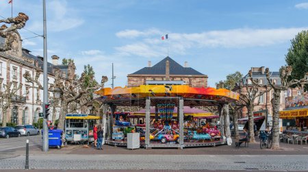 Photo for Strasbourg, France - Oct 28, 2022: Merry-go-round carousel for kids in central PLace Broglie in Strasbourg, Alsace with Opera building in background - Royalty Free Image