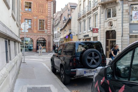 Téléchargez les photos : Strasbourg, France - Oct 28, 2022: Street view of Strasbourg city with black luxury Land Rover Defender Electric Plug-in SUV - en image libre de droit