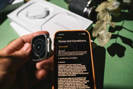 Foto de London, United Kingdom - Sep 23, 2022: Terms and conditions of new titanium Apple Watch Ultra designed for extreme activities during first setup on the dipslay of new Apple iPhone 14 pro - Imagen libre de derechos