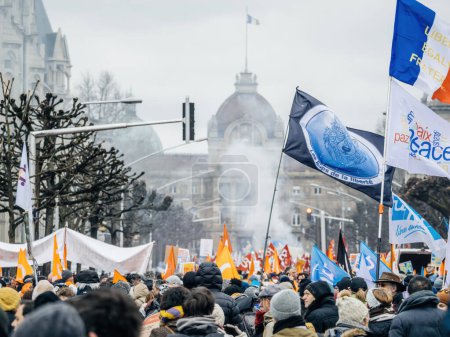 Téléchargez les photos : Strasbourg, France - 31 January 2023: Smoke greande flags and placards - second demonstration against the new pension reform to be presented next month by French Prime Minister Elisabeth Borne - en image libre de droit