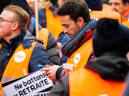 Téléchargez les photos : Strasbourg, France - 31 January 2023: Side view of real human male texting at second demonstration against the new pension reform to be presented next month by French Prime Minister Elisabeth Borne - en image libre de droit
