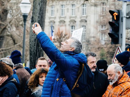 Foto de Strasbourg, France - 31 January 2023: man taking photo with smartphone second demonstration against the new pension reform to be presented next month by French Prime Minister Elisabeth Borne - Imagen libre de derechos