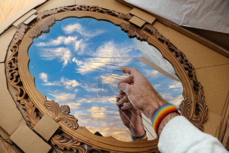 Foto de POV mano masculina que apunta a los detalles del nuevo espejo hermoso vintage de madera con cristales rotos y nubes dispersas reflejadas en - nuevo pedido de Internet dañado durante el transporte - Imagen libre de derechos