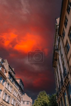 Téléchargez les photos : Vue à angle ultra bas de la maison à colombages alsacienne française et l'architecture haussmannienne avec feu rouge dramatique enfer armagedon ciel entre eux - en image libre de droit