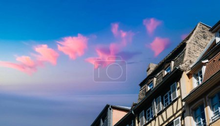 Téléchargez les photos : Vue à angle bas de l'architecture alsacienne française de la maison à colombages avec coucher de soleil nuages ciel - en image libre de droit
